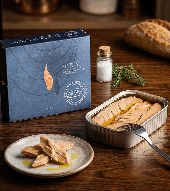 Verpackung mit blauer Hintergrundfarbe, Illustration eines Fischfilets, Text über nachhaltige Fischerei, Bio-Olivenöl und Salz, Logo und Produktbeschreibung.