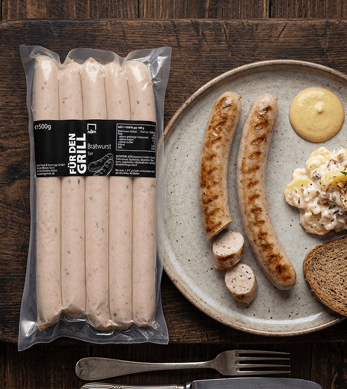 Verschweißte Packung mit fünf rohen Bratwürsten in Naturdarm, hellrosa Farbe mit kleinen Fett- und Gewürzflecken, auf transparentem Kunststoffbeutel.