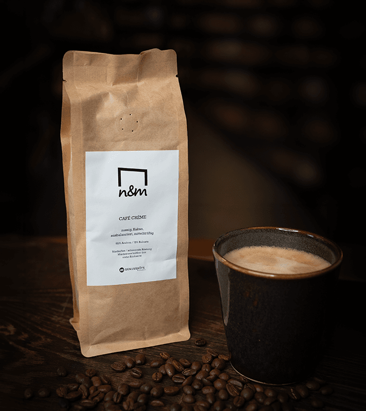 Paket mit Kaffeebohnen neben einer Tasse frisch gebrühtem Kaffee auf einem Holztablett.