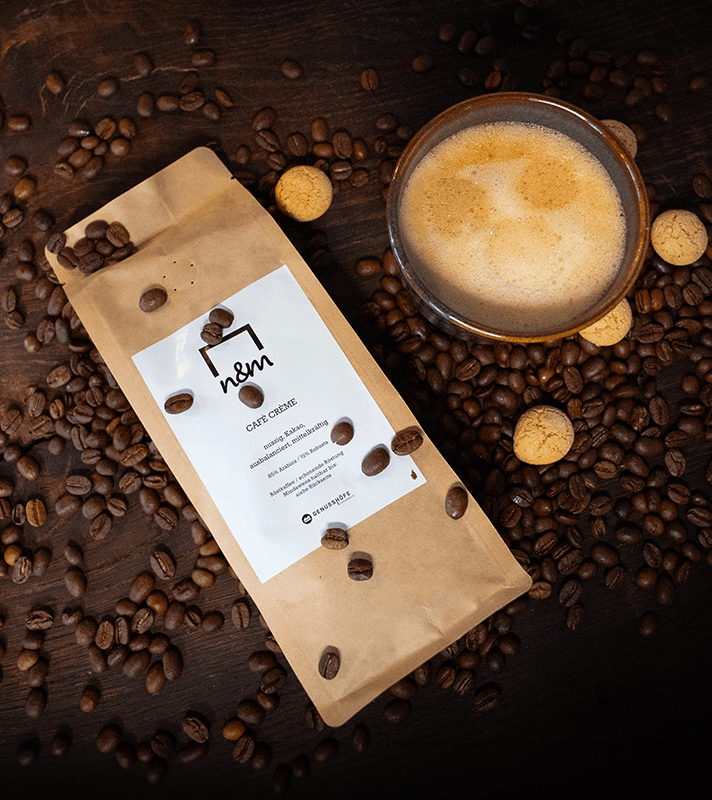 Paket mit Kaffeebohnen neben einer Tasse frisch gebrühtem Kaffee auf einem Holztablett.