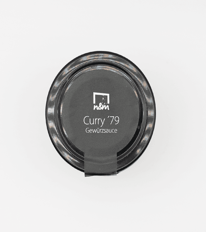 Dunkle Gewürzsoße in einer runden, schwarzen Verpackung mit weißem Label, das "Curry '79" und "Gewürzsoße" beschreibt.