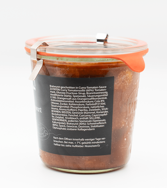 Glas mit rotem Silikonverschluss und Metallclip, gefüllt mit Curry-Tomatenwurst in Curry-Tomaten-Sauce, mit schwarzem Etikett auf der Vorderseite.