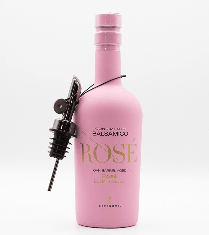 Eine pinke Flasche mit Balsamico-Produkt, inklusive Zapfhahn und Metallhahn, für die Zubereitung von Salaten oder Speisen.