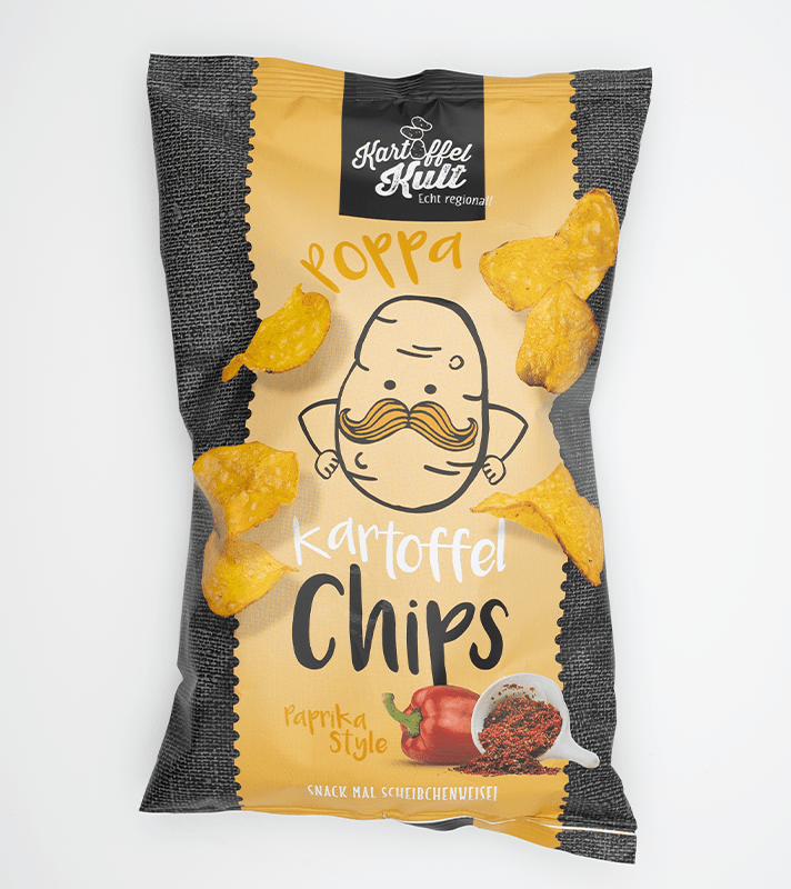 Bunte Verpackung mit Kartoffelchips in Paprika-Style, abgebildet ist ein lachender Kartoffelcharakter mit Schnurrbart, neben einem Paprika und Paprikapulver.