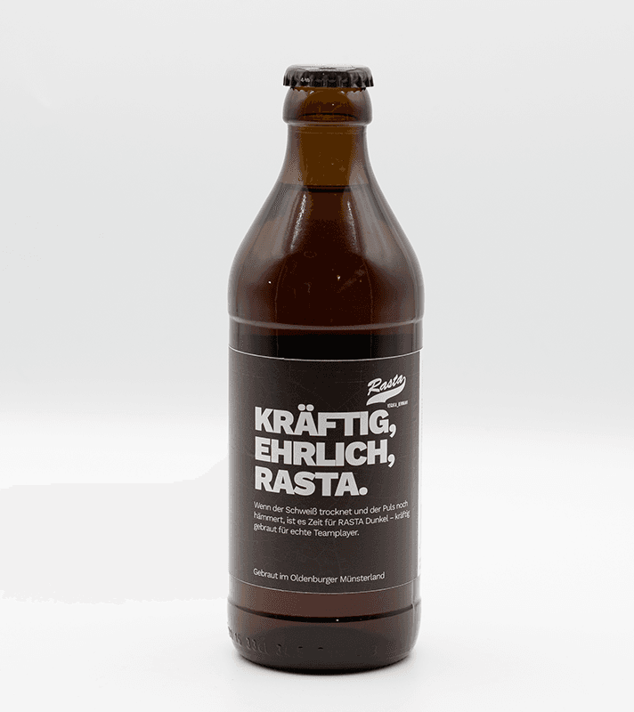 Braune Bierflasche mit schwarzem Etikett, weißer und roter Schrift, Text: "Kräftig, ehrlich, Rasta", und weiteren Beschreibungen auf Deutsch.