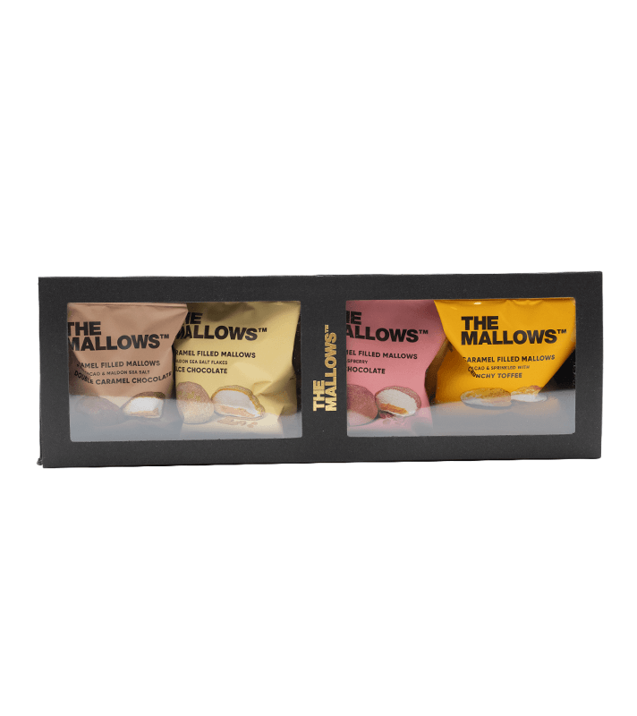 Vier Packung mit gefüllten Marshmallows in verschiedenen Geschmacksrichtungen, sichtbar durch eine transparente Fenster in einer schwarzen Verpackung.
